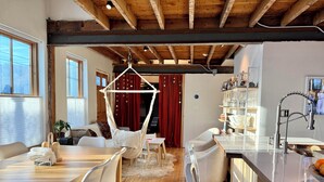 Une cuisine moderne avec un plafond en bois, un fauteuil suspendu et un coin bar.