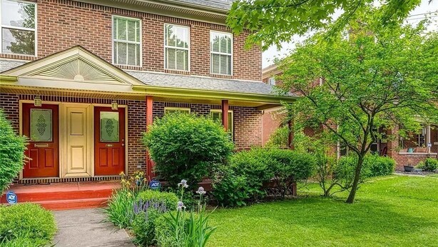 A brick house with a front porch, a well-maintained lawn, and a small garden. - Stylish North Point Breeze Townhome, 3BR/2.5BA, Sleeps 6, Garage Parking (Pittsburgh)