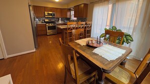 A kitchen with wooden cabinets, a microwave, and an oven. There is a dining table with chairs and a chandelier. - Stylish North Point Breeze Townhome, 3BR/2.5BA, Sleeps 6, Garage Parking (Pittsburgh)