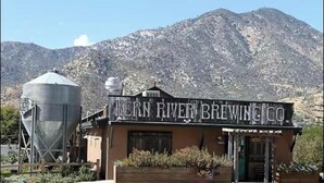 Un edificio con un letrero que dice 'KERN RIVER BREWING CO.' frente a un paisaje montañoso.