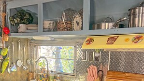 Una cocina de estilo antiguo con estufa amarilla, un lavaplatos y diferentes utensilios de cocina.