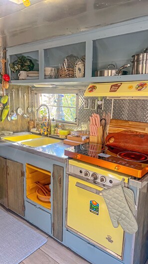 Une cuisine d’époque avec un poêle jaune, un évier et divers ustensiles de cuisine.