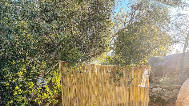 Un espacio de estar al aire libre con cojines, una mesita pequeña y un farol decorativo.