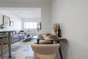 A modern living room with a sofa, coffee table, and dining table.