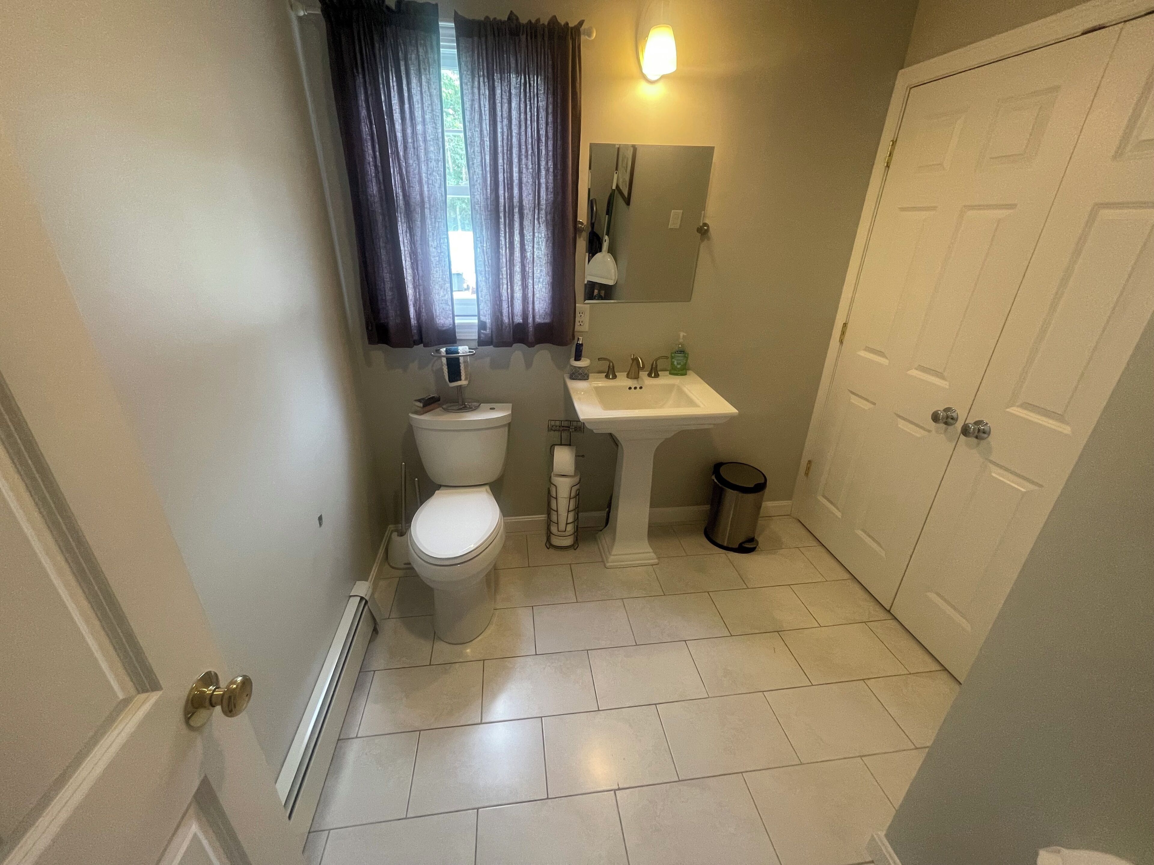 A small bathroom with a toilet, sink, and a mirror.