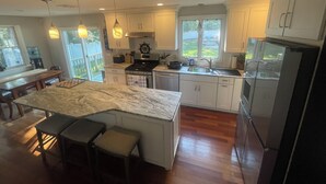 Una cocina moderna con armarios blancos, una isla grande y un refrigerador de acero inoxidable.