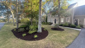 Una casa residencial con jardín delantero, entrada para vehículos y calle.