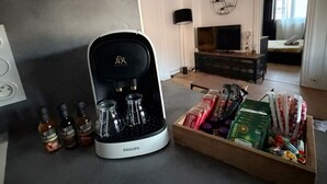 A modern kitchen with a coffee maker, bottles of syrup, and a tray of snacks.