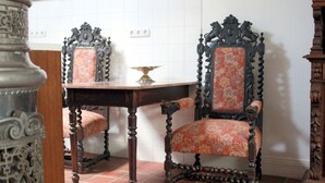 Une pièce au décor traditionnel, avec une table en bois et des chaises richement décorées, un mur recouvert de carreaux et un pilier ornemental.