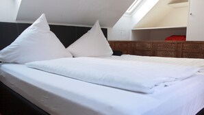Un lit bien fait, avec des oreillers, une tête de lit en bois et une lucarne au-dessus.