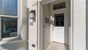 Fachada blanca de una casa con el número '123' en la pared, una puerta y una ventana.