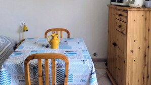 Una zona de menjador amb una taula posta per a dues persones, un armari de fusta i un mirall penjat a la paret.