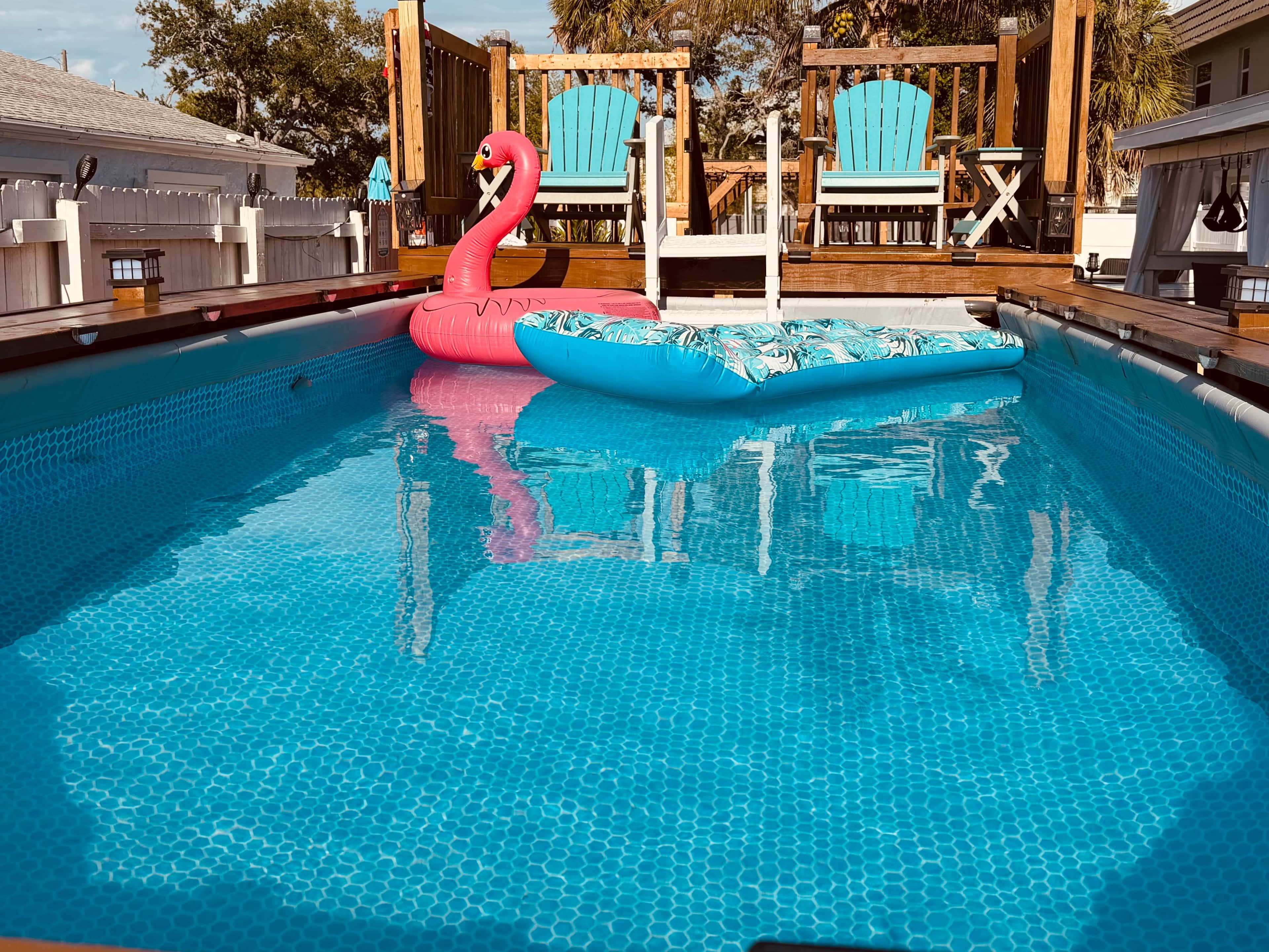 Une piscine avec un flotteur en forme de flamant rose et un canapé gonflable bleu.