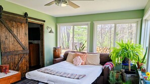 A bedroom with a bed, a ceiling fan, a window, and a rustic wooden door. - Beautiful private home located in Lewiston Michigan. (Lewiston)