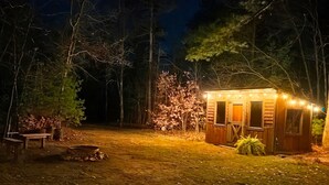 A small wooden cabin with a porch, surrounded by trees and a fire pit. - Beautiful private home located in Lewiston Michigan. (Lewiston)