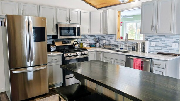 A modern kitchen with stainless steel appliances, white cabinets, and a wooden ceiling. - Beautiful private home located in Lewiston Michigan. (Lewiston)