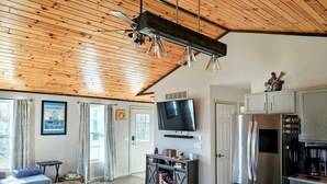 A modern kitchen with a large refrigerator, stove, and microwave. There is a dining table and a sofa in the living area. - Beautiful private home located in Lewiston Michigan. (Lewiston)