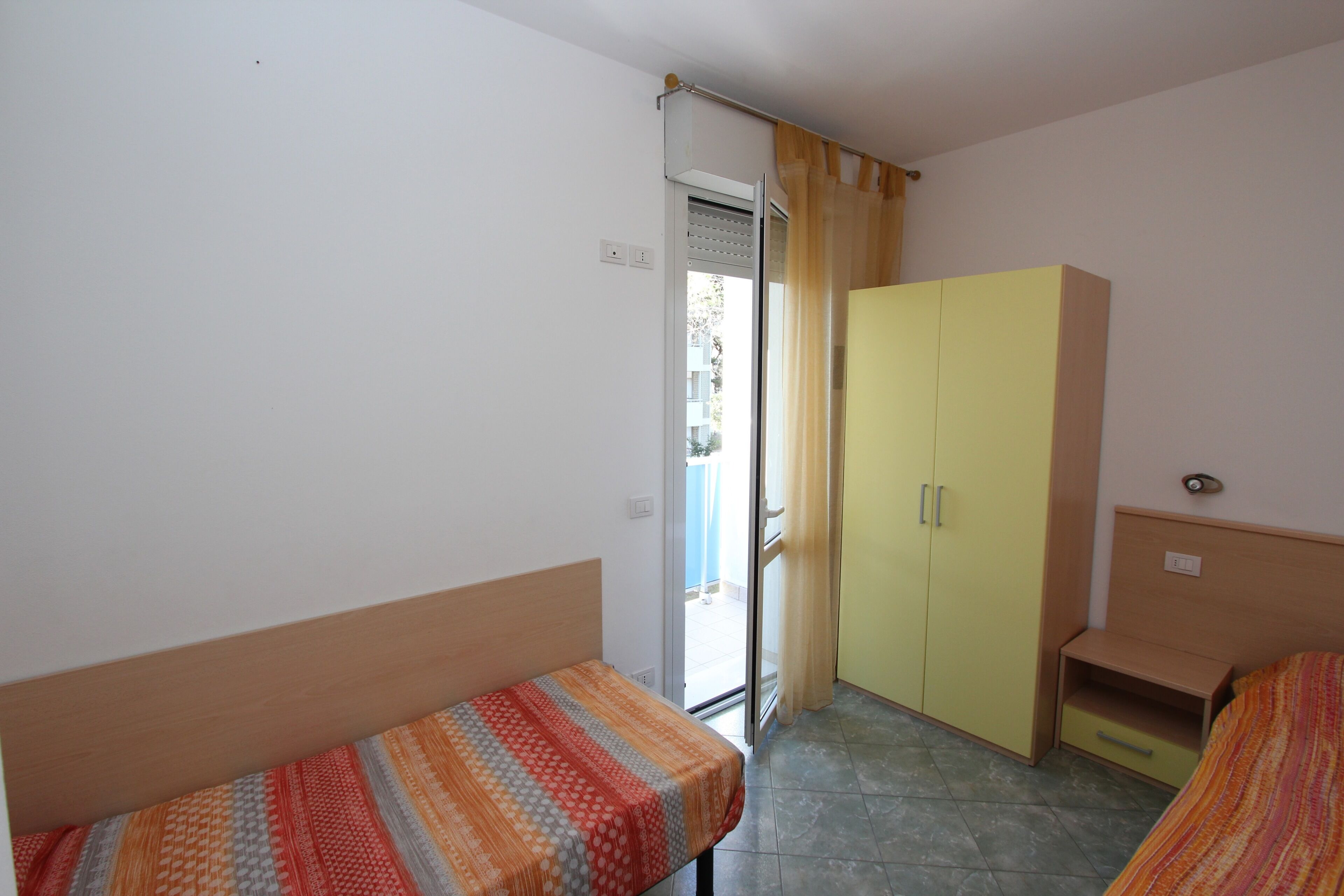 Une petite pièce avec un lit, une armoire et une fenêtre.