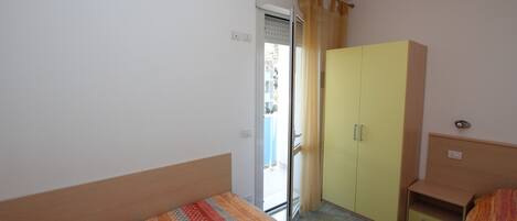 Une petite pièce avec un lit, une armoire et une fenêtre.