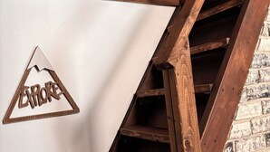 Una escalera de madera con un letrero triangular que dice 'EXPLORE' frente a una pared blanca.
