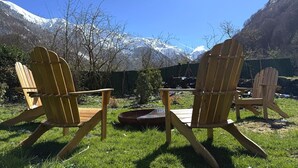 Deux fauteuils Adirondack en bois, placés face à une chaîne de montagnes enneigées.