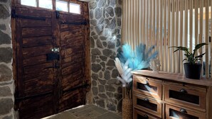 Une porte en bois rustique, un mur en pierre, un meuble en bois avec des tiroirs et une plante en pot.