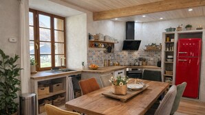 Une cuisine avec une table en bois, des chaises, un réfrigérateur rouge et une fenêtre donnant sur un beau paysage.