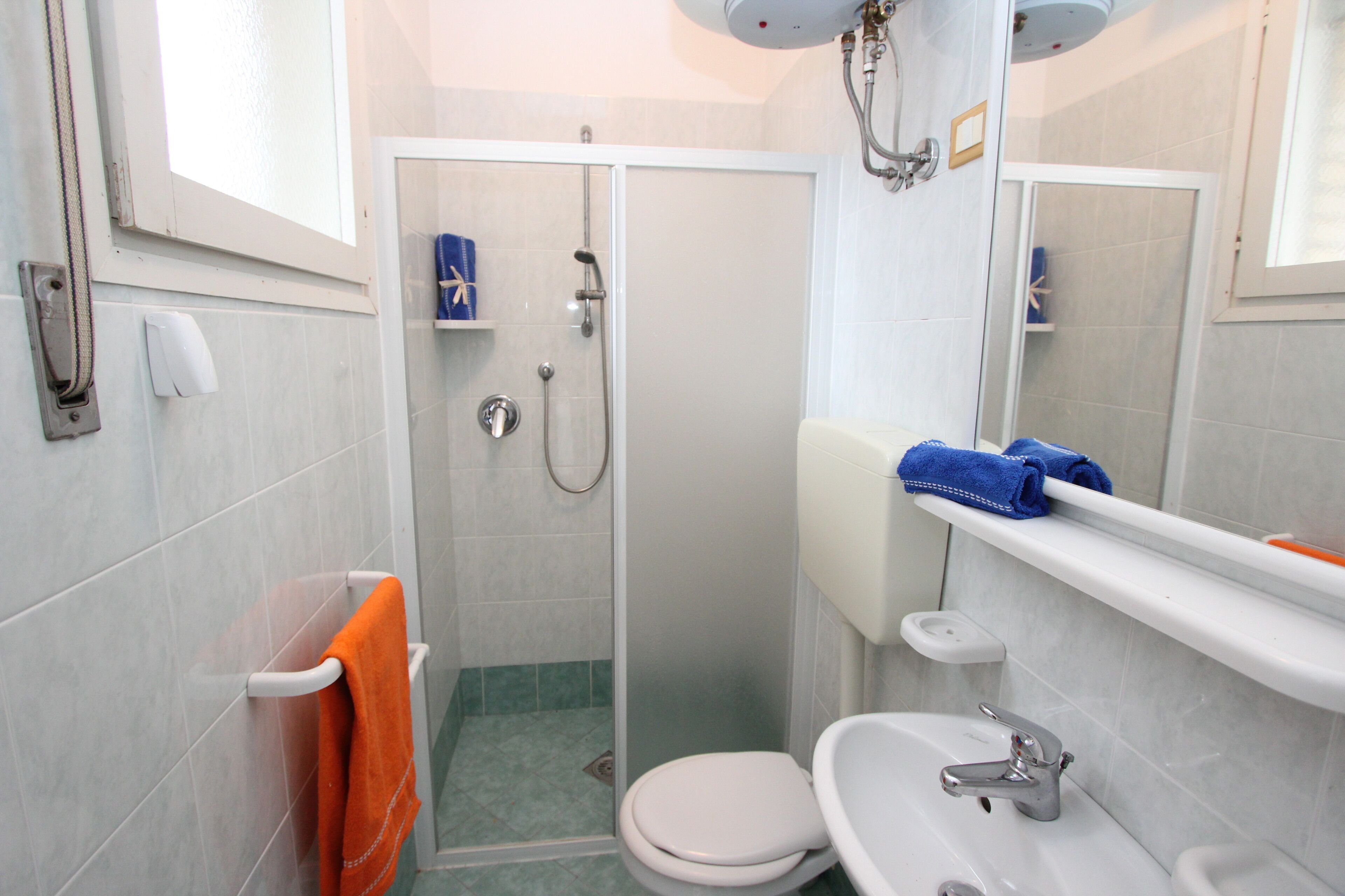 Une salle de bain équipée d’une douche, de toilettes, d’un lavabo et d’un porte-serviettes avec une serviette.