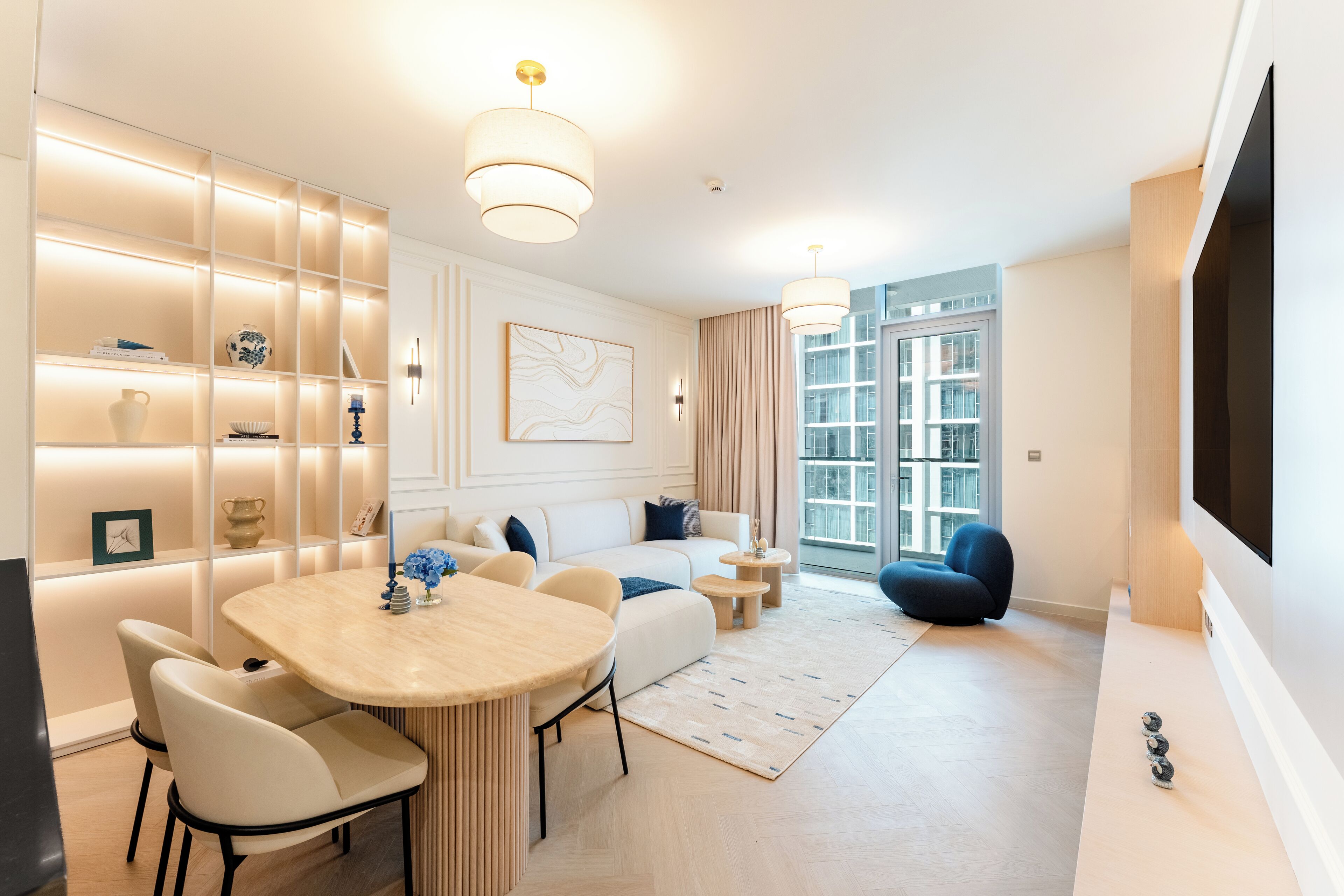 Een moderne woonkamer met een eethoek, een zithoek, een televisie en een groot raam.
