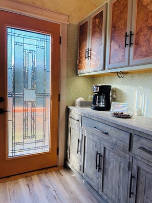 A kitchen with a frosted glass door, wooden cabinets, and a coffee maker on the counter.