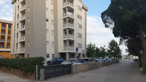 Un edificio residenziale a più piani con balconi, un'area di parcheggio e cielo sereno.