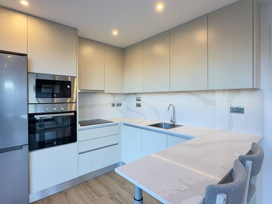 Una cocina moderna con horno integrado, microondas y refrigerador de acero inoxidable.
