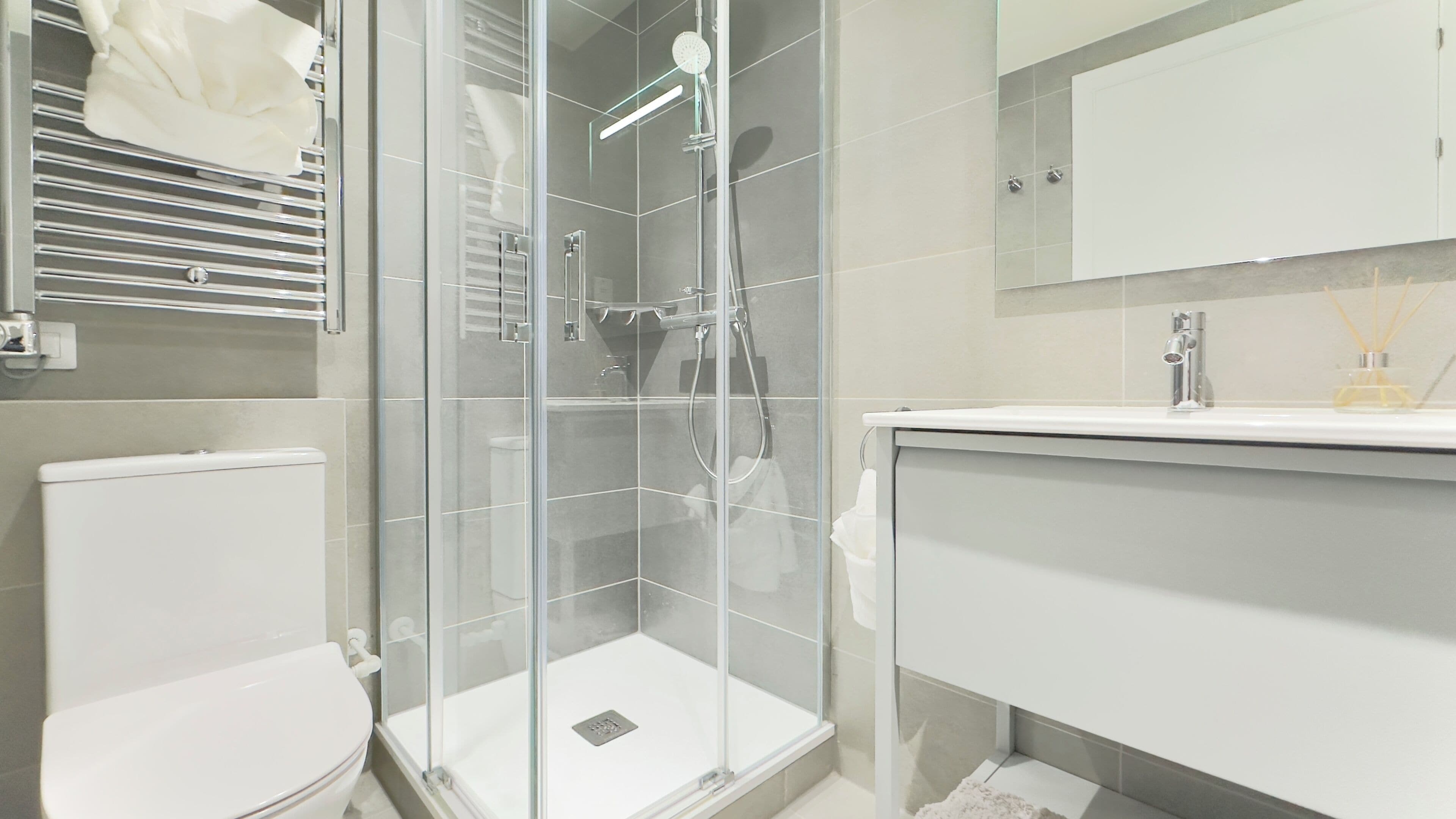 Une salle de bain moderne dotée d’une douche à parois de verre, de toilettes et d’un meuble-lavabo avec un miroir.
