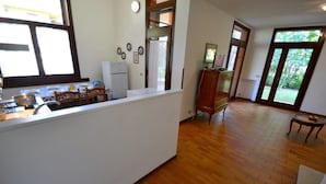 A kitchen with a wooden floor, a white counter, and a dining area with chairs.