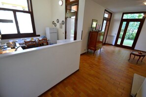 A kitchen with a wooden floor, a white countertop, and a refrigerator.