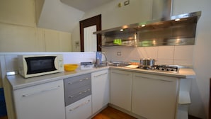 A compact kitchen with white cabinets, a microwave, a gas stove, and a sink.