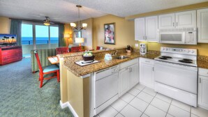 A hotel kitchen with a dining area, a microwave, an oven, and a view of the ocean. - NCAA - Walk to Daytona Beach Bandshell - Ocean Walk - 1 BD (Daytona Beach)