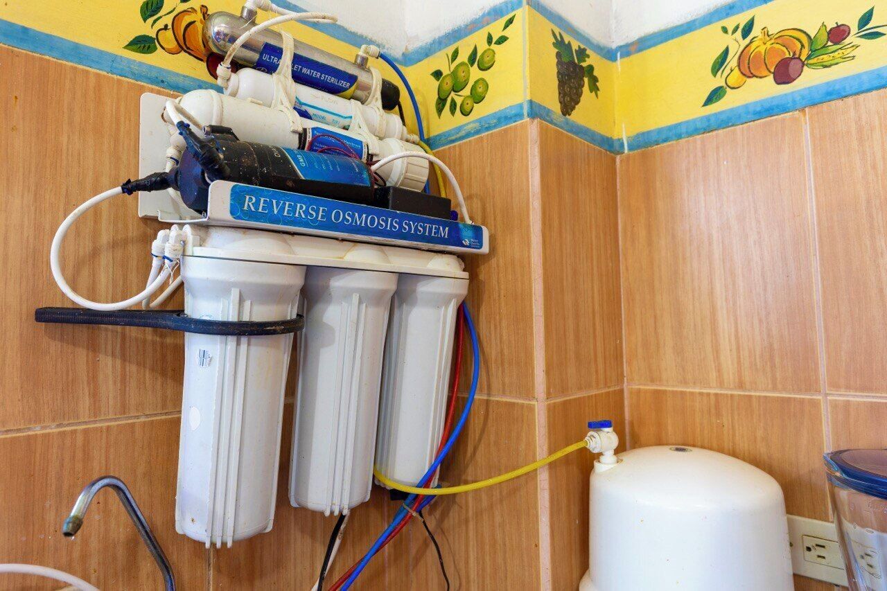 Een omgekeerde osmose waterfiltersysteem geïnstalleerd in een badkamer met betegelde wanden en een fruitmotiefrand.