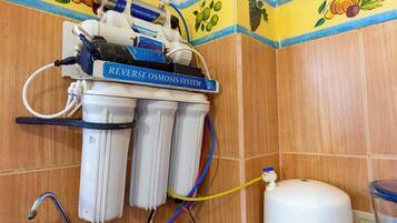 Een omgekeerde osmose waterfiltersysteem geïnstalleerd in een badkamer met betegelde wanden en een fruitmotiefrand.