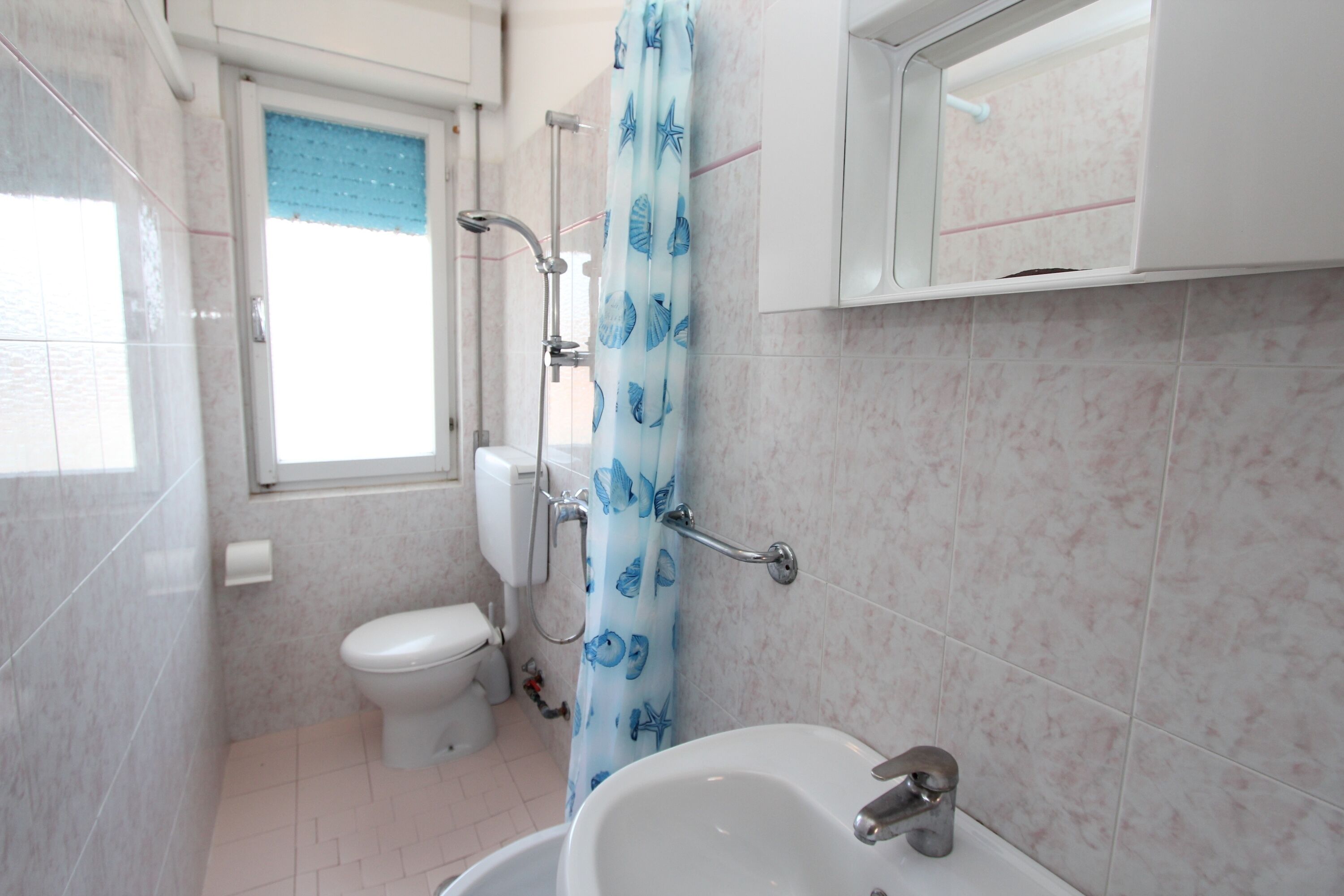 A bathroom with a toilet, shower, and sink.