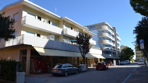 Ett hotell med flera våningar, balkonger, en parkeringsplats och en klar himmel.