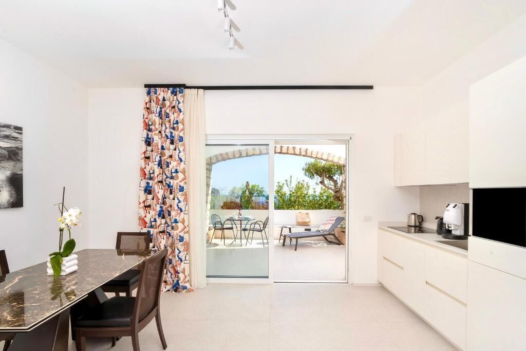A modern kitchen with a dining area, a sliding glass door leading to an outdoor patio, and a small TV on the counter.