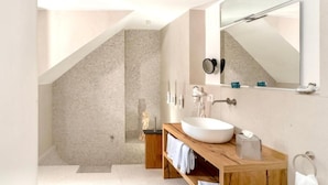 Une salle de bain moderne avec un lavabo sur pied, un grand miroir et un espace douche.