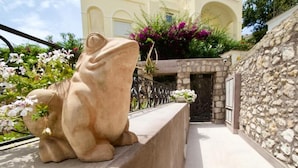 Un mur de pierre, un banc de pierre et une statue de pierre représentant une grenouille.