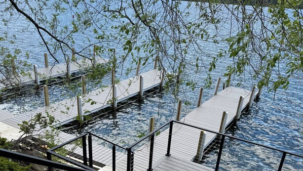 Une jetée en bois s’étendant sur une étendue d’eau calme, entourée d’arbres et sous un ciel dégagé.