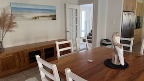 A dining area with a wooden table, white chairs, a decorative sculpture, and a painting of a beach scene. - Beach Haven – Spacious Coastal Retreat in Dalyellup (Dalyellup)