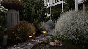 A stone pathway leading through a garden with various plants and a decorative stone structure. - Beach Haven – Spacious Coastal Retreat in Dalyellup (Dalyellup)