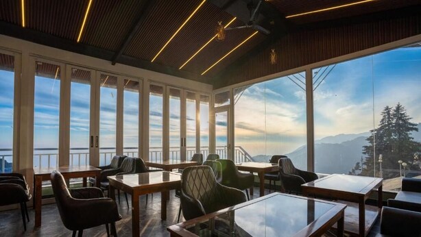 Un espace intérieur vaste et lumineux, avec de grandes fenêtres, des meubles en bois et une vue sur les montagnes.