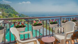 Un balcon agrémenté de fauteuils en osier, de plantes en pot et offrant une vue sur un paysage montagneux.