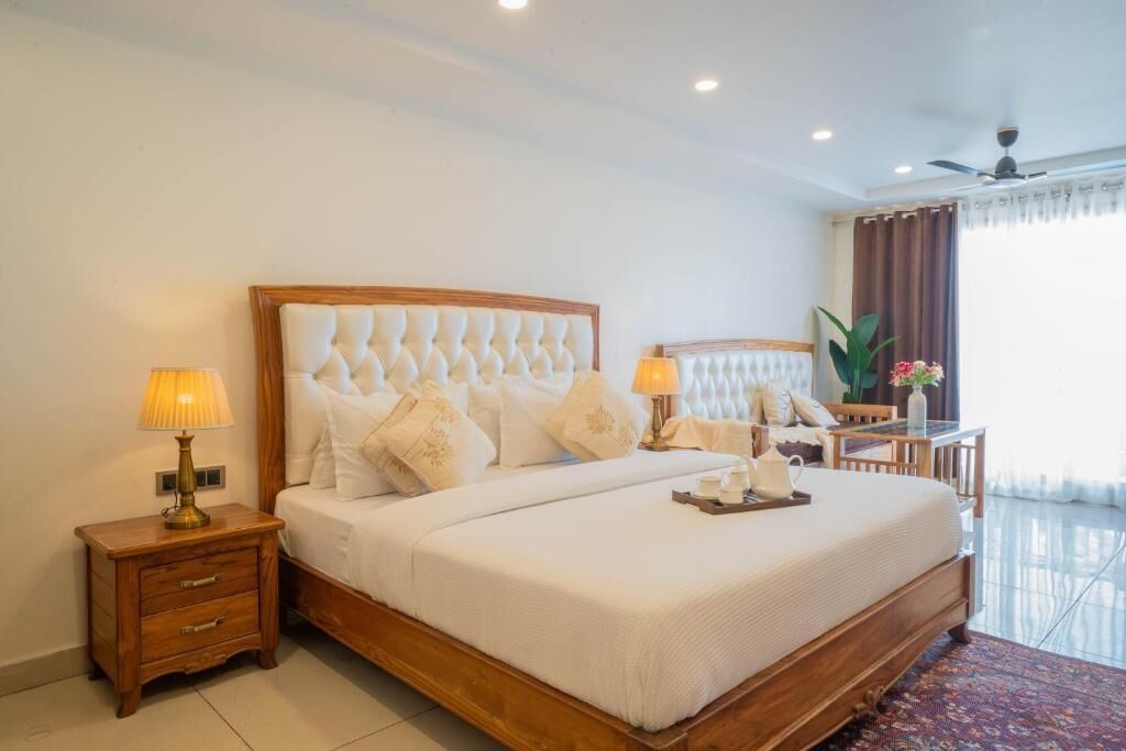 A hotel room with a large bed, bedside lamps, a desk with a chair, and a window with curtains.